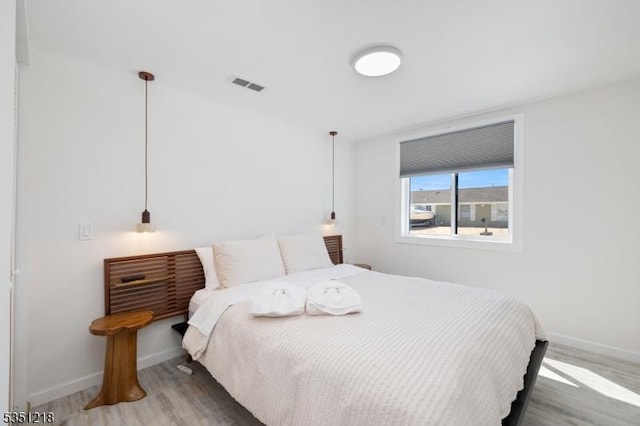 bedroom featuring wood finished floors, baseboards, and visible vents