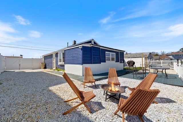 back of house featuring an outdoor fire pit, a patio, fence, and a gate