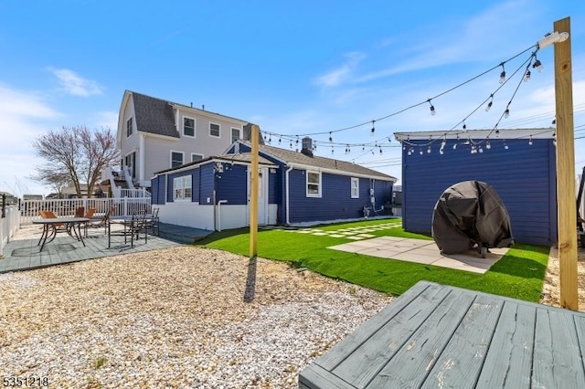 rear view of property featuring a patio area, fence, a lawn, and an outbuilding