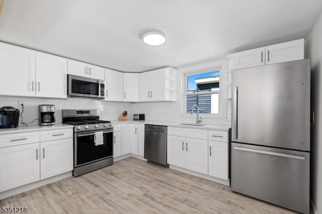 kitchen featuring white cabinets, light countertops, a sink, and appliances with stainless steel finishes