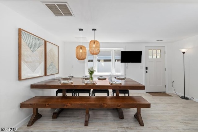 dining space with light wood-type flooring, visible vents, and baseboards
