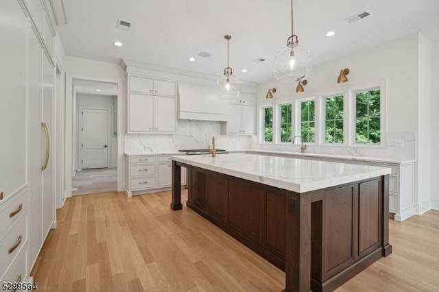 kitchen featuring light wood-type flooring, premium range hood, white cabinets, backsplash, and recessed lighting