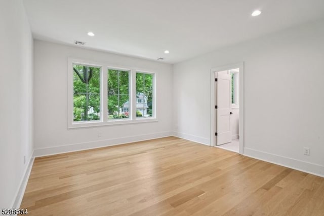 empty room featuring baseboards, light wood-style floors, visible vents, and recessed lighting