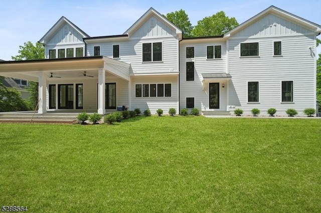 rear view of property featuring board and batten siding, ceiling fan, and a yard