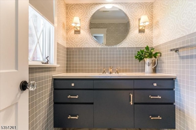 bathroom featuring wallpapered walls, tile walls, vanity, and ornamental molding