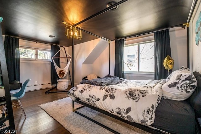bedroom with wood finished floors and baseboard heating