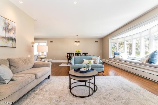living room featuring a baseboard radiator, wood finished floors, and a wealth of natural light