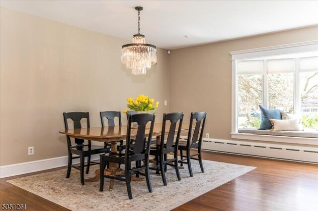 dining room featuring baseboard heating, baseboards, wood finished floors, and a chandelier
