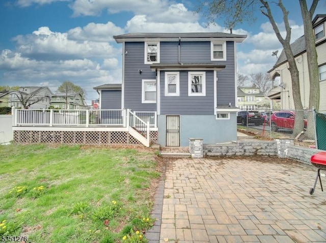 back of property with a yard, fence, a deck, and a patio area