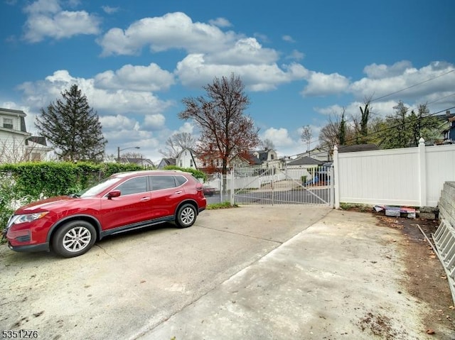 view of parking with fence and a gate