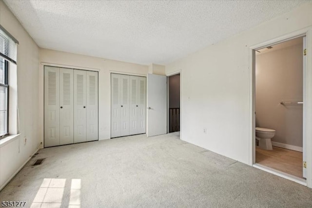 417 Penns Way, Bernards Twp, NJ 07920 - unfurnished bedroom featuring carpet flooring, multiple closets, a textured ceiling, and ensuite bath