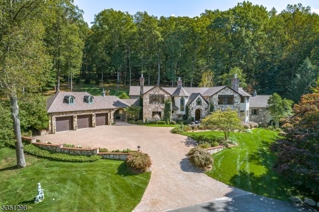 view of front facade featuring stone siding, driveway, a garage, a front yard, and a chimney