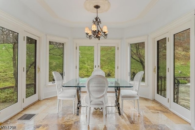sunroom / solarium with french doors, stone tile floors, and a chandelier