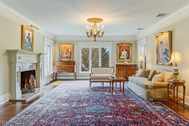 sitting room featuring a chandelier, ornamental molding, wood finished floors, a baseboard heating unit, and baseboards
