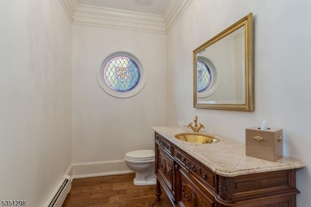 half bath with ornamental molding, toilet, vanity, a baseboard heating unit, and wood finished floors