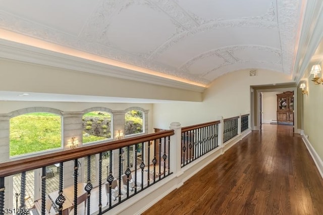 corridor featuring wood finished floors, baseboards, and lofted ceiling