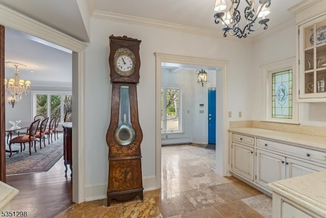foyer entrance featuring a chandelier, ornamental molding, a baseboard heating unit, and baseboards