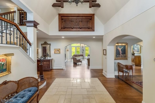 entryway featuring arched walkways, high vaulted ceiling, a baseboard radiator, wood finished floors, and ceiling fan