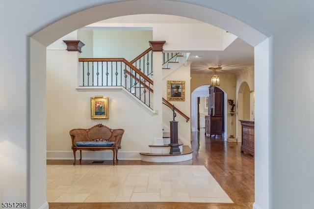 stairs with arched walkways, baseboards, and recessed lighting