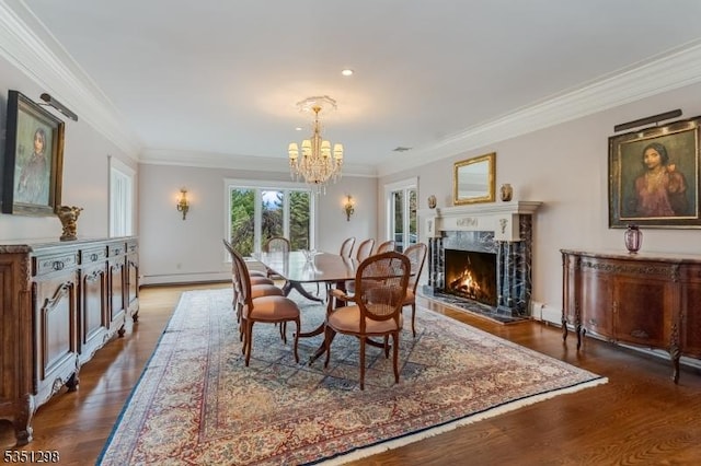 dining room featuring a chandelier, ornamental molding, a high end fireplace, wood finished floors, and a baseboard heating unit
