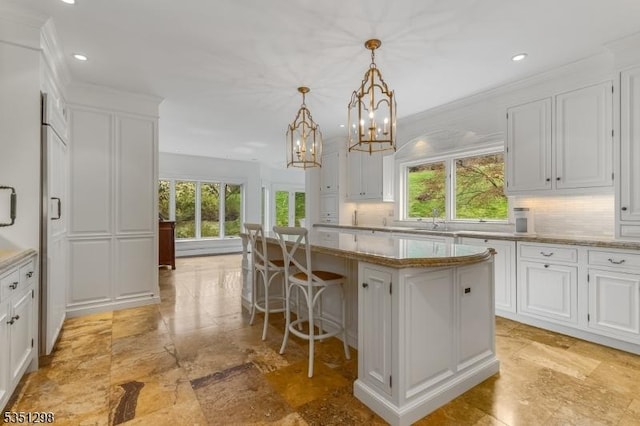 kitchen featuring decorative backsplash, a kitchen island, plenty of natural light, white cabinetry, and recessed lighting