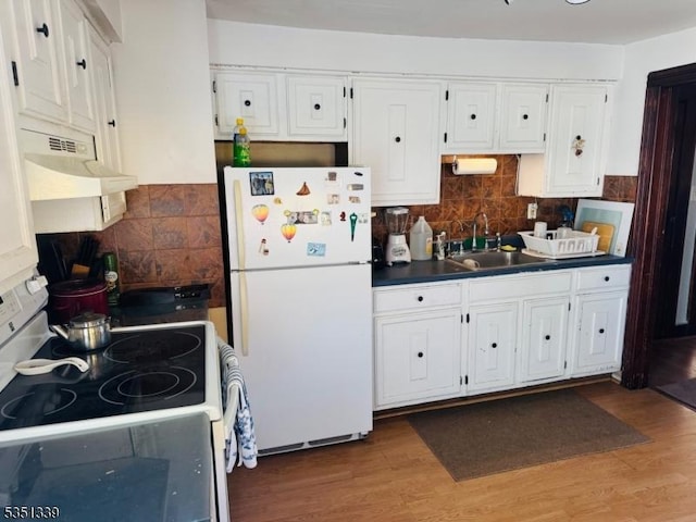 kitchen featuring white appliances, a sink, dark countertops, and backsplash