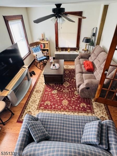 living area featuring radiator heating unit, wood finished floors, and a ceiling fan