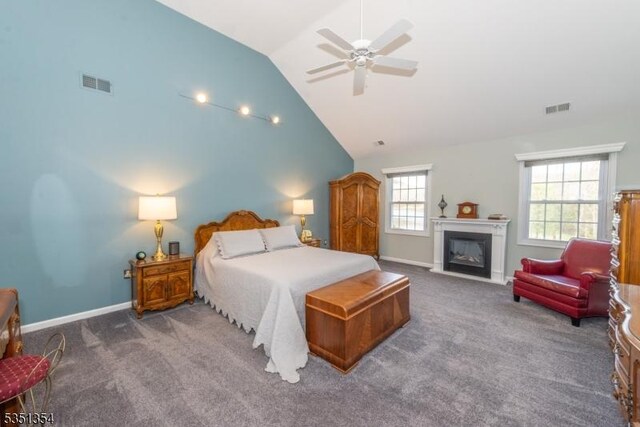 bedroom featuring carpet flooring, visible vents, vaulted ceiling, and a glass covered fireplace
