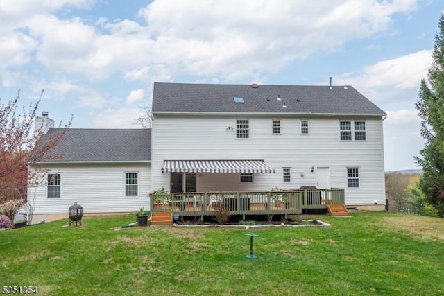 rear view of house with a wooden deck, a yard, and a chimney