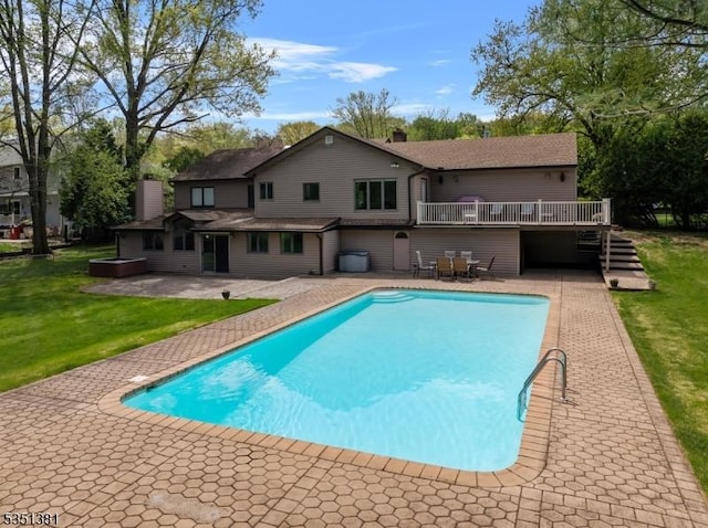 outdoor pool with a yard, a patio area, a deck, and stairway