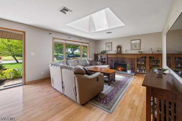 living area with a skylight, a wealth of natural light, light wood-type flooring, and visible vents
