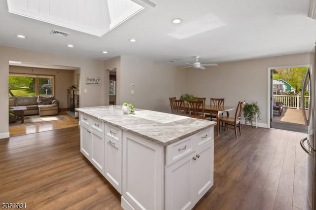 kitchen with a center island, white cabinets, wood finished floors, and a wealth of natural light