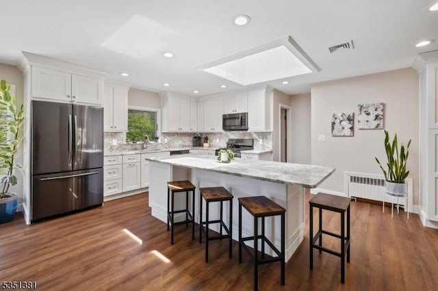kitchen featuring a sink, stove, radiator heating unit, freestanding refrigerator, and visible vents