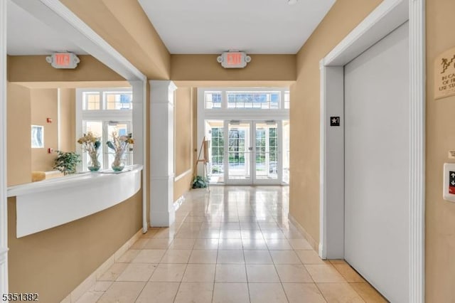 corridor featuring elevator, baseboards, french doors, and light tile patterned floors