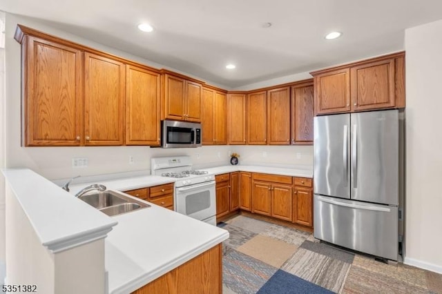 kitchen featuring brown cabinetry, stainless steel appliances, and a sink