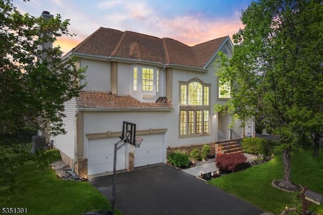 view of front of property featuring an attached garage, a lawn, stucco siding, and driveway