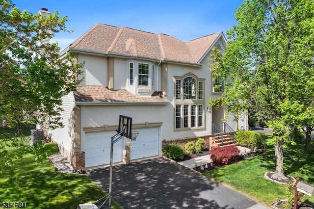 traditional home featuring a garage, a front lawn, aphalt driveway, and stucco siding