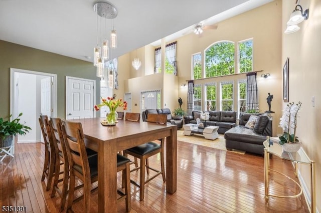 dining area with baseboards, a towering ceiling, and hardwood / wood-style flooring