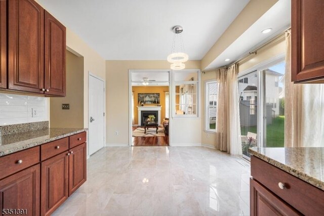 kitchen with decorative backsplash, light stone counters, pendant lighting, and a wealth of natural light