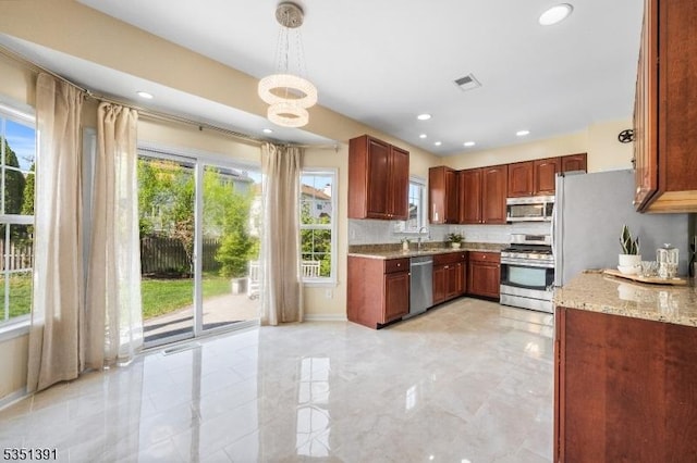 kitchen featuring light stone countertops, appliances with stainless steel finishes, plenty of natural light, and visible vents