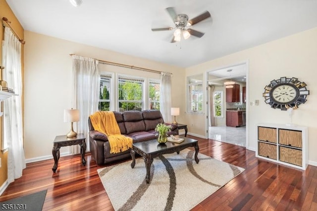 living area featuring baseboards, ceiling fan, and wood finished floors