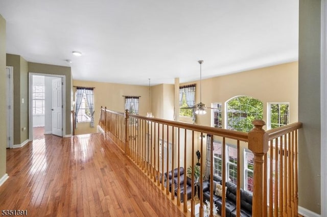 corridor with baseboards, an upstairs landing, and hardwood / wood-style floors