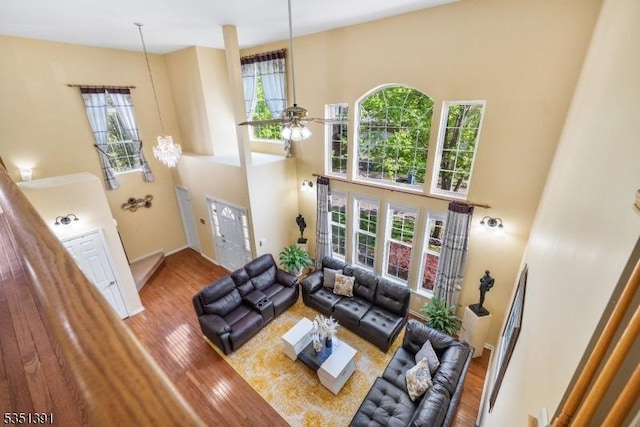living room with a wealth of natural light, wood finished floors, and a towering ceiling