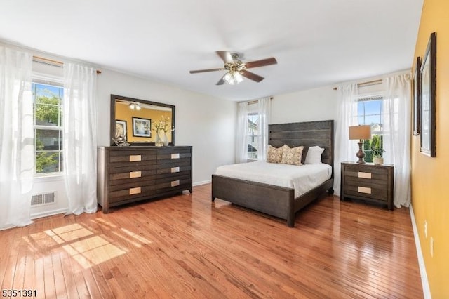 bedroom with visible vents, a ceiling fan, wood-type flooring, and baseboards