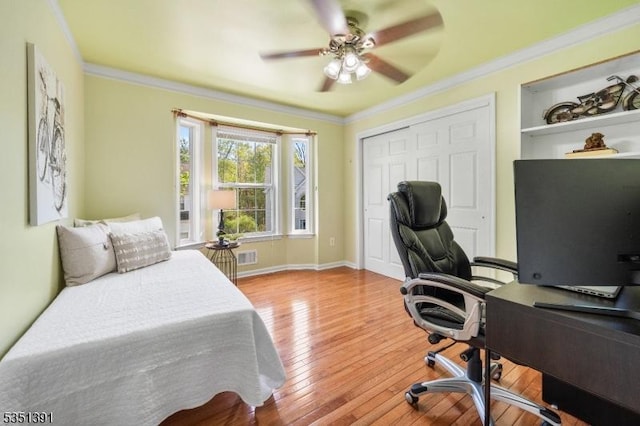 bedroom featuring wood-type flooring, crown molding, ceiling fan, and a closet