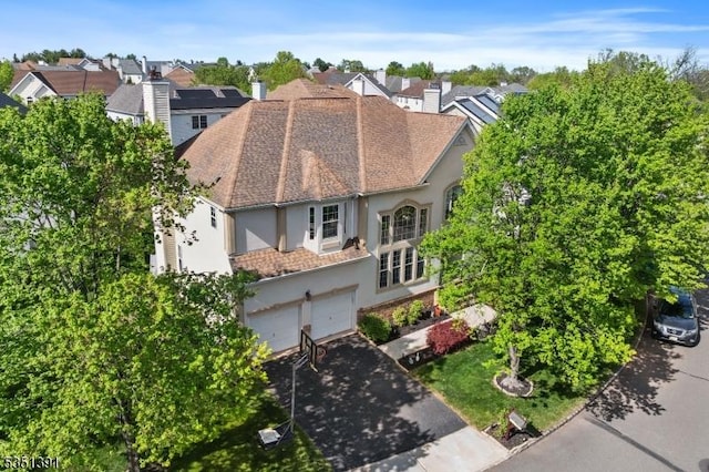 view of front of house featuring an attached garage, aphalt driveway, stucco siding, and a residential view