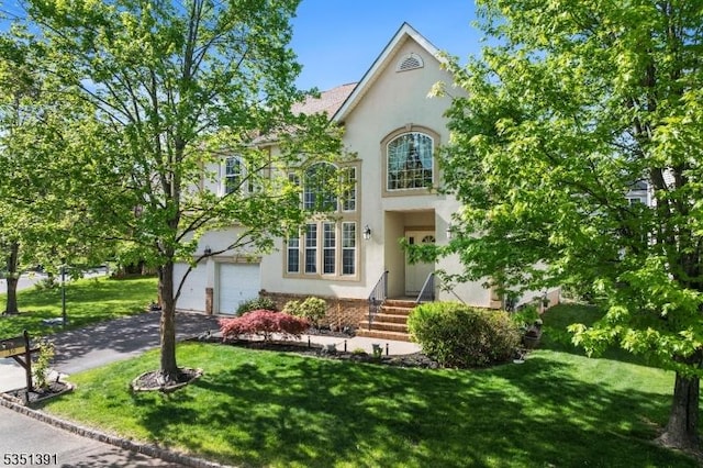 view of front of property with a garage, stucco siding, driveway, and a front yard