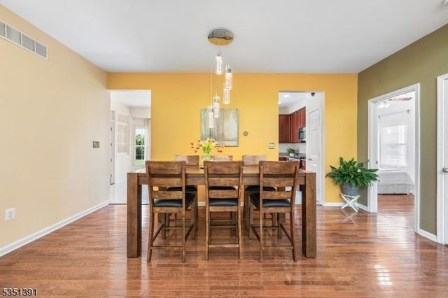 dining room with baseboards, visible vents, and wood finished floors