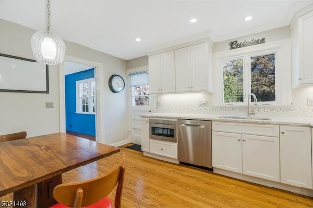 kitchen with plenty of natural light, a sink, white cabinets, light wood finished floors, and stainless steel appliances