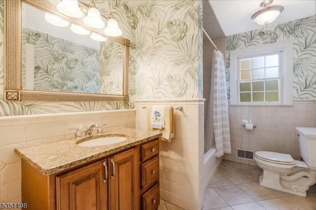 bathroom with toilet, tile patterned floors, wallpapered walls, tile walls, and visible vents
